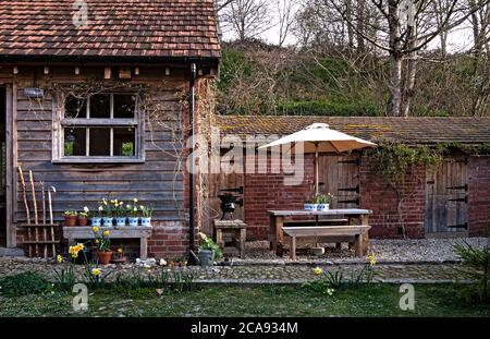 Frühlingsgartenlandschaft mit Picknicktisch und Sonnenschirm Stockfoto