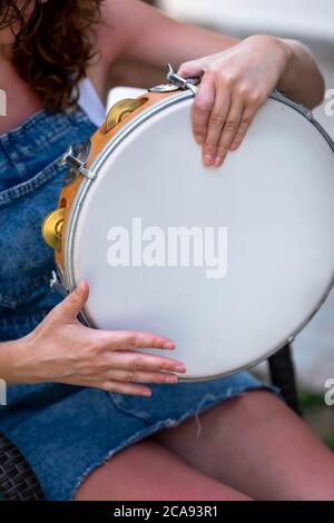 Frau hält in seiner Hand ein Folk Tamburin in Griechenland. Seitenprofil einer Frau, die ein Tamburin Instrument spielt. Stockfoto