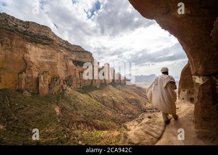 Rückansicht von Priest Wandern auf dem Zufahrtsweg zu den Felsen gehauen Abuna Yemata Guh Kirche, Gheralta Berge, Tigray Region, Äthiopien, Afrika Stockfoto