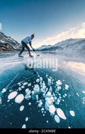 Mann spielt Eishockey auf dem gefrorenen Sils See, Engadin, Kanton Graubünden, Schweiz, Europa Stockfoto