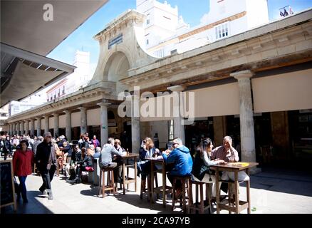 Besucher des Lebensmittelmarktes in Cadiz essen auf Tischen und Hockern im Freien Stockfoto