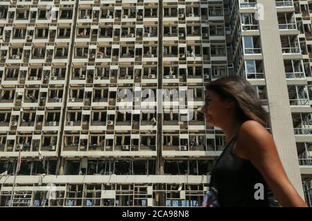 Beirut, Libanon. August 2020. Eine Libanesin geht vor die zerstörte Fassade des libanesischen Elektrizitätsgebäudes, das von einer massiven Explosion im Hafen von Beirut betroffen war, die die ganze Stadt erschütterte, mindestens 100 Menschen tötete und Tausende verletzte. Quelle: Marwan Naamani/dpa/Alamy Live News Stockfoto