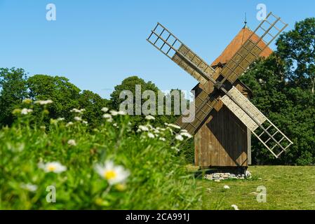 Alte alte hölzerne Windmühle im Hintergrund des Sommerfeldes. Saaremaa, Estland. Stockfoto