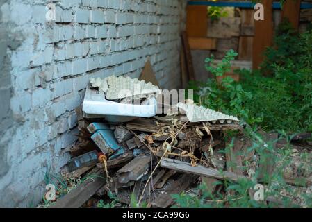 Altes Waschbecken auf einem verlassenen Haus, Müllkippe, vor dem Hintergrund einer strukturierten weißen Ziegelwand. Verschmutzung der Umwelt. Antikes Waschbecken Stockfoto