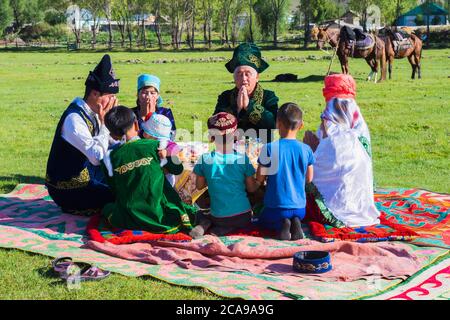 Kasachische Familie in traditioneller Kleidung betete vor dem Mittagessen, für redaktionelle nur, Sati Dorf, Tien Shan Gebirge, Kasachstan verwenden Stockfoto