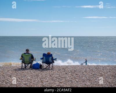 Aldeburgh, Suffolk, Großbritannien. August 2020. Die Menschen genießen den Kiesstrand an der Nordsee an einem warmen Sommertag mit einer steifen Brise, während der aktuelle heiße Zauber im Osten Englands weitergeht. Kredit: Julian Eales/Alamy Live Nachrichten Stockfoto