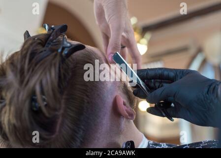 Barber Rasieren ein junger bärtiger Barbier Shop Kunde Kerl mit einem Rasiermesser. Nahaufnahme. Barthaare, gefährliche Rasiermesser, professionelle Haare und Bartpflege. Mann Stockfoto