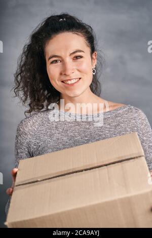 Glücklich lächelnde Frau erhielt großen Kasten, der in ihren Händen hält Stockfoto