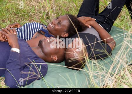 Glückliche Gruppe von jungen Freunden liegen auf dem Gras im Freien und Blick über den Himmel Stockfoto