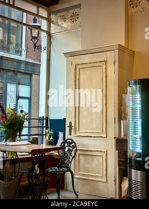 Inneneinrichtung des Café-Restaurants, Speisesaal, Tisch im klassischen Stil und Stühle mit altem Schrank an der Wand. Dezente Pastellfarben. Blumenvase im Schaufenster. Nobody Copy Space Konzept. Retro-Vintage-Look. Stockfoto