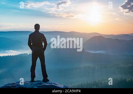 Wanderer beobachten Herbstsonne am Horizont . Schöner Moment. Spektakuläre Bergketten Silhouetten. Mann erreicht Gipfel genießen Freiheit Stockfoto