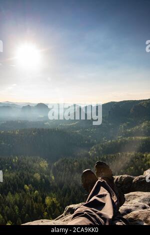 Müde Einzeltourist sitzt am Rande vor der Kulisse einer unglaublichen Berglandschaft Stockfoto