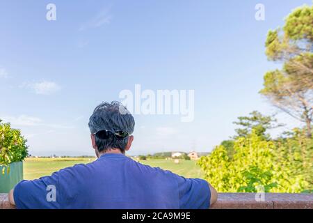 Ein Mann schaut aus, um eine schöne Landschaft zu betrachten, die Sonnenbrille in der Rückseite trägt, als ob er Augen hinter seinem Kopf hatte Stockfoto