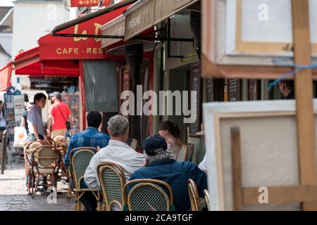 Touristen und Besucher sitzen in den Restaurants rund um den Place du Tertre Platz und beobachten die Maler. Stockfoto