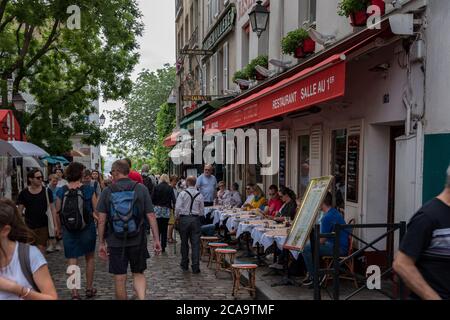 Touristen und Besucher sitzen in den Restaurants rund um den Place du Tertre Platz und beobachten die Maler. Stockfoto