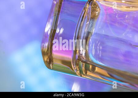 Abstraktes Wasser fällt auf bunte Oberfläche. Abstraktes Hintergrundkonzept mit Glas-Nahaufnahme Stockfoto