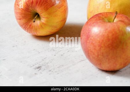 Rote und gelbe Äpfel (kiku Sorte) auf weißem Brett, Nahaufnahme mit Platz für Text links unten. Stockfoto