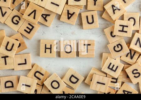 Draufsicht, Stapel von quadratischen Holzblöcken mit heißen Worten auf der weißen Tafel. Stockfoto