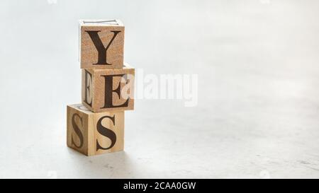 Stapel mit drei Holzwürfeln - Wort JA auf ihnen, Platz für mehr Text / Bilder auf der rechten Seite. Stockfoto