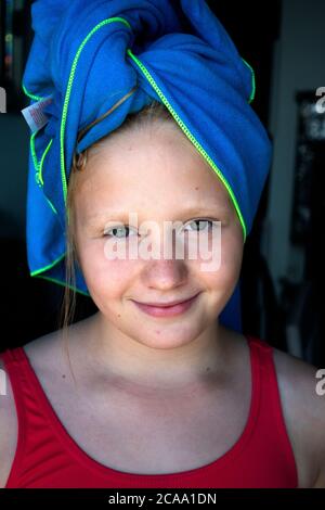 Polnische preteen Mädchen mit einem blauen Handtuch umwickelt nasse Haare lächelnd. Zawady Gmina Rzeczyca Polen Stockfoto