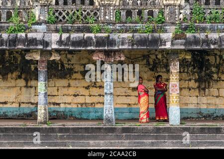 Mayiladuthurai, Tamil Nadu, Indien - Februar 2020: Zwei indische Frauen Pilger stehen neben den alten bunten geschnitzten Steinsäulen im Inneren der alten Stockfoto