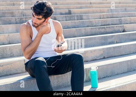 Sportlicher Mann setzt Kopfhörer auf, um Musik während des Trainings, urbanes Sportkonzept und gesunden Lebensstil zu hören, kopieren Raum für Text Stockfoto