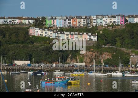 Früh AM MORGEN Blick auf den Hafen von Brixham. Reihe von bunten Häusern in zwei Reihen über dem Hafen an der Skyline. Boote auf Liegeplätzen unter dem Blue Sky Landscape Format. Stockfoto