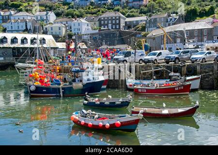 Fischerboote und kleine Boote, die in den Hafengebäuden von Mevagissey festgemacht sind Im Hintergrund mit Blick auf Hafen Landschaft Format Stockfoto