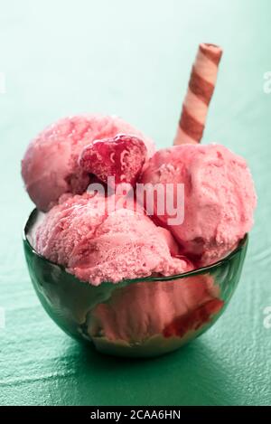 Schale Himbeer-Eisbecher, hausgemacht, isoliert auf einem mintgrünen Hintergrund. Nahaufnahme der Eisschüssel mit Fruchtgeschmack. Sommergenuss. Stockfoto