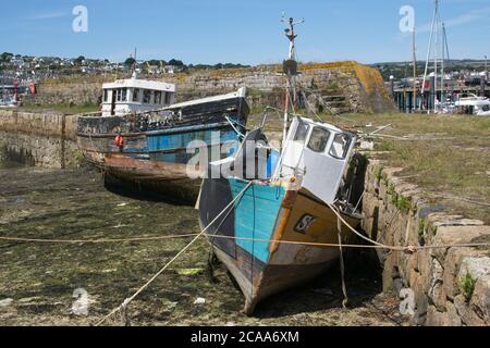 Verfallende Trawler jenseits der Reparatur und Verfall liegen an der Außenwand des Old Harbour Newlyn abblätternde Lackierung, verrottet Holzrumpf Landscape Format Stockfoto