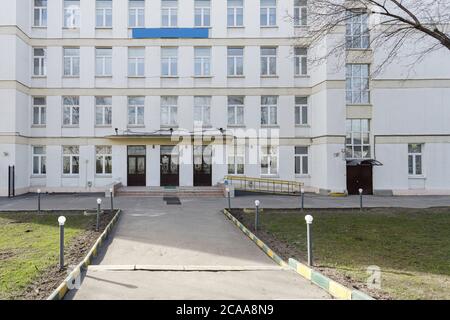 Schulgebäude mit leerem Innenhof. Klassisches lichtverputztes Schulhaus in Moskau, ein typisches Gebäude für Bildungseinrichtungen in den 30-50er Jahren Stockfoto