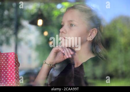 Mädchen in einem schwarzen Kleid sitzt auf der Straßenbahn Stockfoto