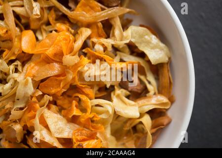 Eine große Schmorlvoll frittierter hausgemachter Chips aus Karotten, Pastinaken und Süßkartoffeln. Dorset England GB Stockfoto