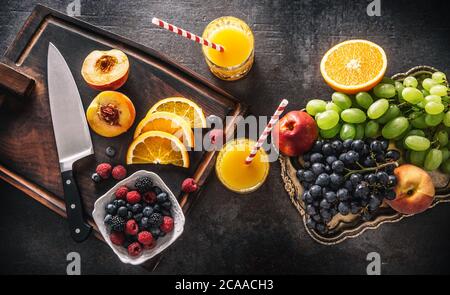 Top of view frische Früchte Saft Orange Trauben Pfirsich Beeren Auf Betontisch Stockfoto