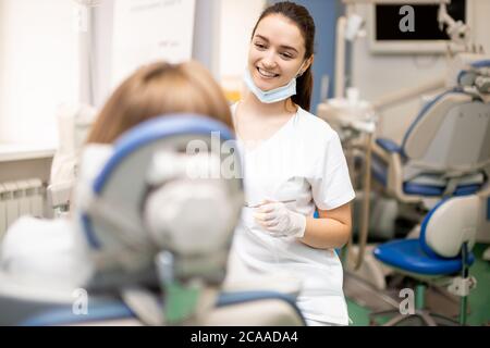 Sorgfältige professionelle Zahnarzt in weißen Uniform Behandlung der Zähne des Patienten, so dass perfekte Lächeln für Patienten, mit medizinischen Geräten Stockfoto