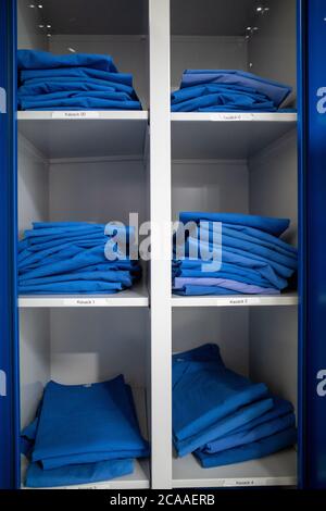 In einem Krankenhaus gibt es ein Regal mit blauer Krankenhauskleidung Stockfoto