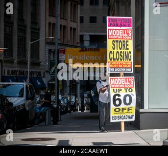 Ein Arbeiter in Lower Manhattan hält ein Schild, auf dem steht, dass die familieneigene Sportartikelkette Modell's schließt, gesehen in New York am Sonntag, den 2. August 2020. Die 131 Jahre alte Kette hat Insolvenzschutz beantragt und schließt alle 115 Filialen. (© Richard B. Levine) Stockfoto