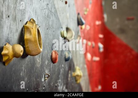 Bunte künstliche Kletterwand in Boulderhalle, Nahaufnahme Stockfoto