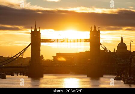 Die Sonne geht hinter der Tower Bridge und der Kuppel der St. Paul's Cathedral unter, wenn das warme Wetter anhält. Stockfoto