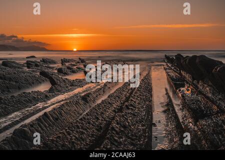 Schöne Aufnahme eines orangen Sonnenuntergangs auf der Flysch in Sakoneta Strand, Gipuzkoa, Baskenland Stockfoto