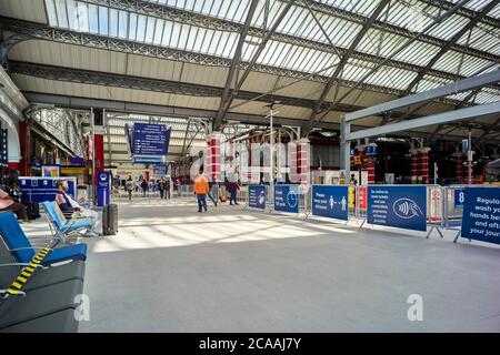 Liverpool Lime Street Station mit Personal und Passagieren, die Gesichtsmasken tragen und große Schilder mit Ratschlägen zu Covid-19 Stockfoto