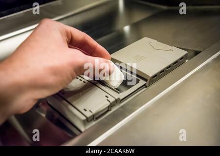 Nahaufnahme eines Mannes, der die Waschmitteltablette in die Spülmaschine legte Stockfoto