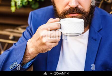 Bartmann hält Kaffee oder Kaffeetasse im Café am Morgen. Tasse Kaffee. Cappuccino und schwarze Espresso-Kaffeetasse. Kaffeegetränk. Bärtiger Mann, Hände Stockfoto