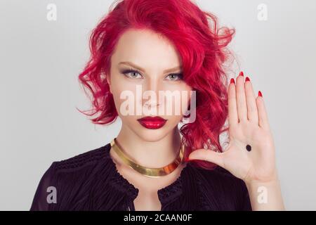 Frau mit schwarzem Punkt auf der Handfläche geben ein Signal über häusliche Gewalt. Roter Kopf lockig bob Frisur Mädchen isoliert hellgrau grau weiß Hintergrund. Mischen Stockfoto
