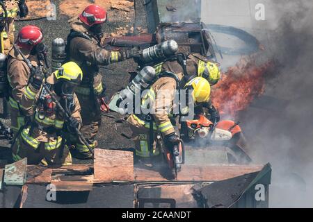 Feuerwehrmann mit Axt und Hecht Polce auf beteiligt Dach auf Feuer Stockfoto