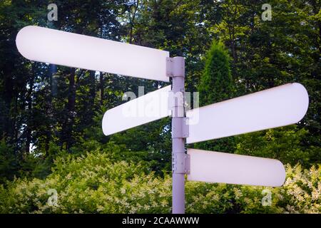 Leeres Hinweisschild in einem öffentlichen Park. An einem sonnigen Tag zeigt der leere Pfeilpfosten den Weg nach draußen. Stockfoto