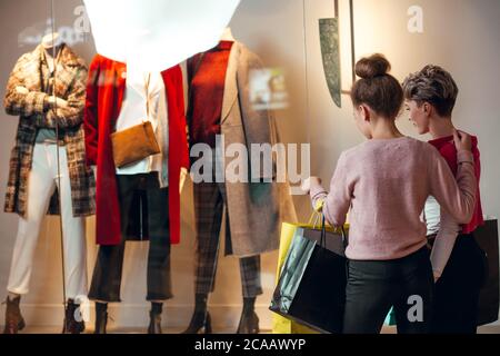 Zwei weibliche Shopoholic Freunde Blick auf Schaufenster der Lady s Wear Frauen Kollektion Boutique, Rückansicht. Stockfoto