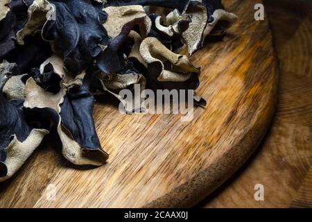 Nahaufnahme von trockenen schwarzen geschnittenen Pilzen auf Holzhintergrund. Essbarer dunkler Pilz - auricularia polytricha. Niemand Stockfoto