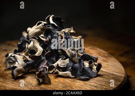 Nahaufnahme von trockenen schwarzen geschnittenen Pilzen auf Holzhintergrund. Essbarer dunkler Pilz - auricularia polytricha. Niemand Stockfoto