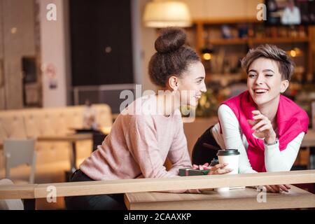 Weibliche fröhliche Mitarbeiter zusammen zu Mittag essen, in der Mall, Geselligkeit und tratschen über Kollegen Stockfoto